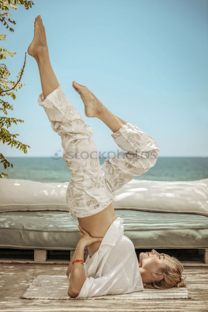 Caucasian blonde woman practicing yoga in the beach