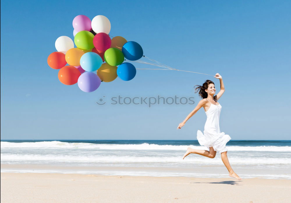 Father and daughter with balloons playing on the beach at the day time. Concept of friendly family.