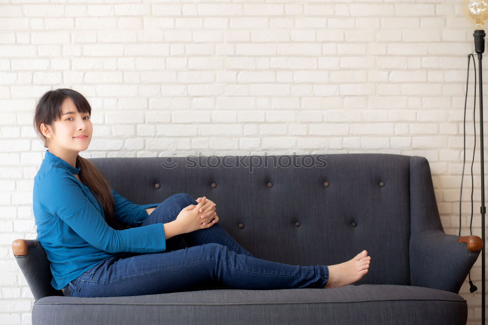 Young woman sits on the couch and sticks out one leg