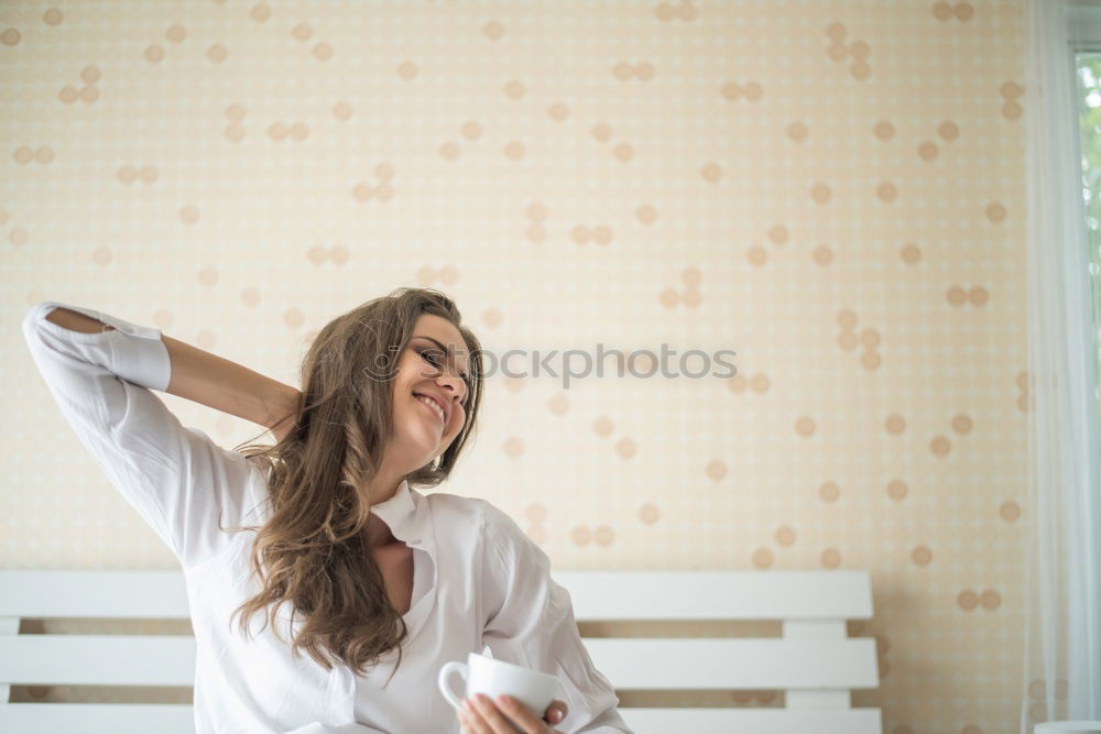 young slim redhead woman with curls sits barefoot in hot pants on parquet floor and looks at camera