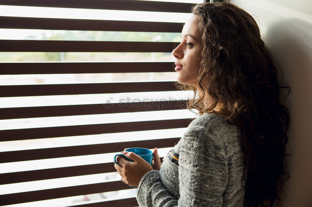 Similar – young, redheaded woman with curls looks out of the balcony window