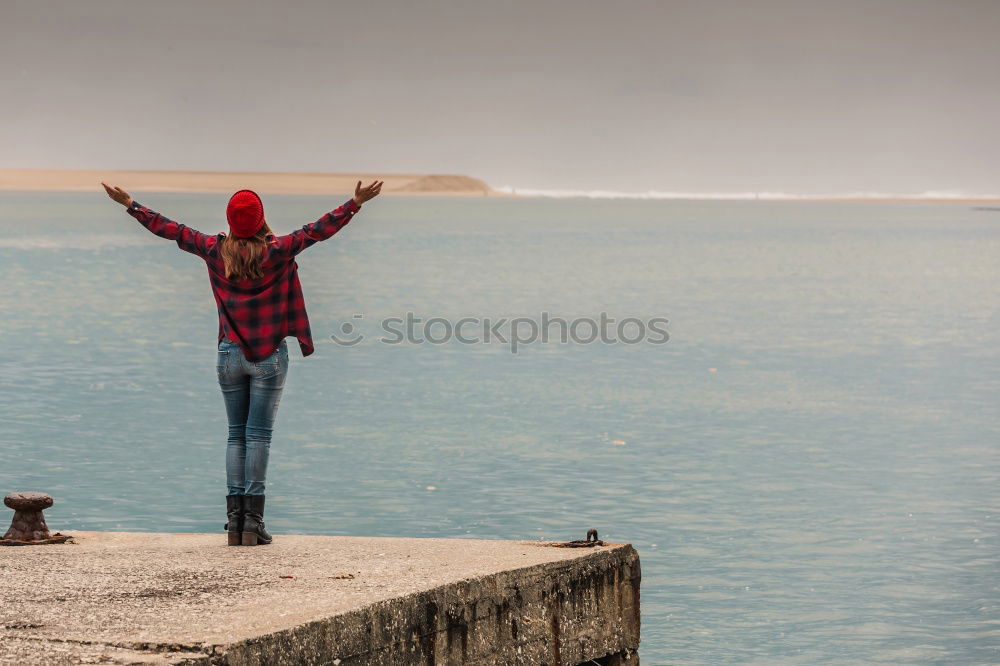 Similar – Girl with arms raised standing on the cliff