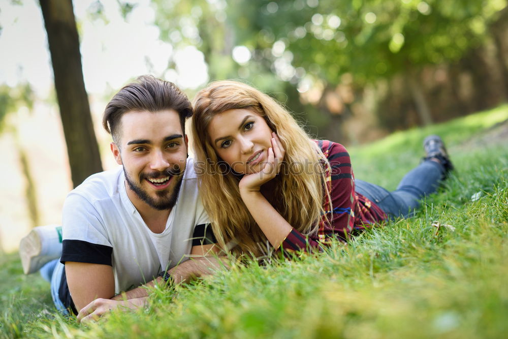 Beautiful young couple laying on grass in an urban park