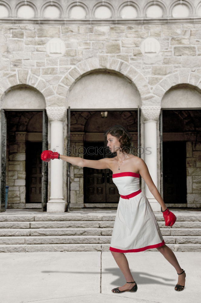 Similar – elegantly dressed lady with black coat, red hat, red scarf and red pumps is dancing on a large square with concrete and patterned floor