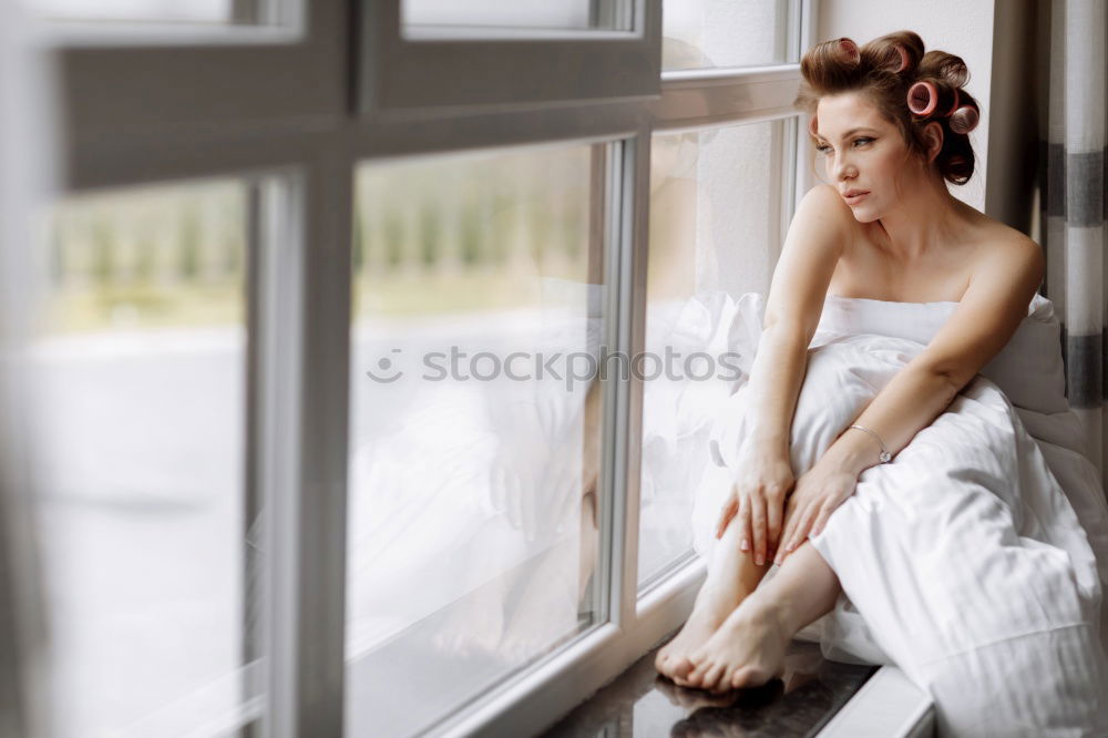 Similar – Young woman in sweater and socks sits in the window frame of a kitchen in the morning