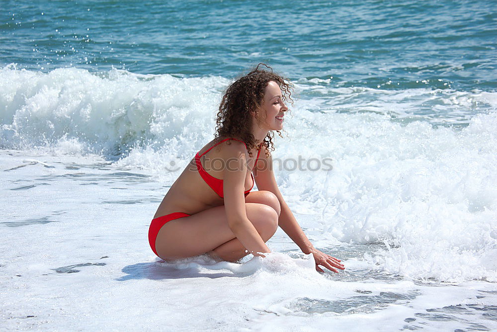 Beautiful young woman in sexy bikini standing at sea beach. Beautiful woman in violet bikini on tropical beach. Portrait of brunette tanned girl in swimwear