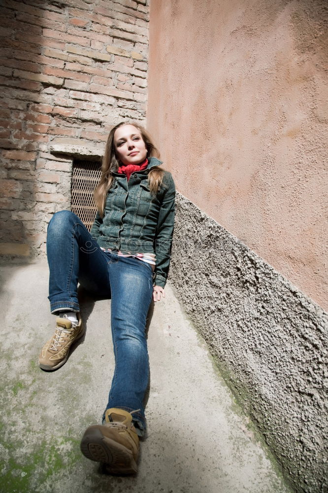 Similar – thoughtful woman with dreadlocks, in jeans and brown leather jacket is standing at an old dilapidated house wall