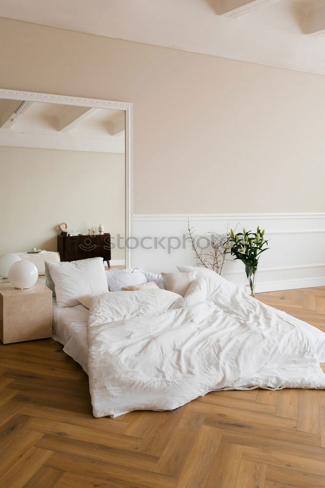 Similar – Ein Doppelbett mit weißer Bettwäsche und beigen Kissen in einem hellen skandinavischen Schlafzimmer, ein Bett auf dem Boden und Blumen in einer Vase