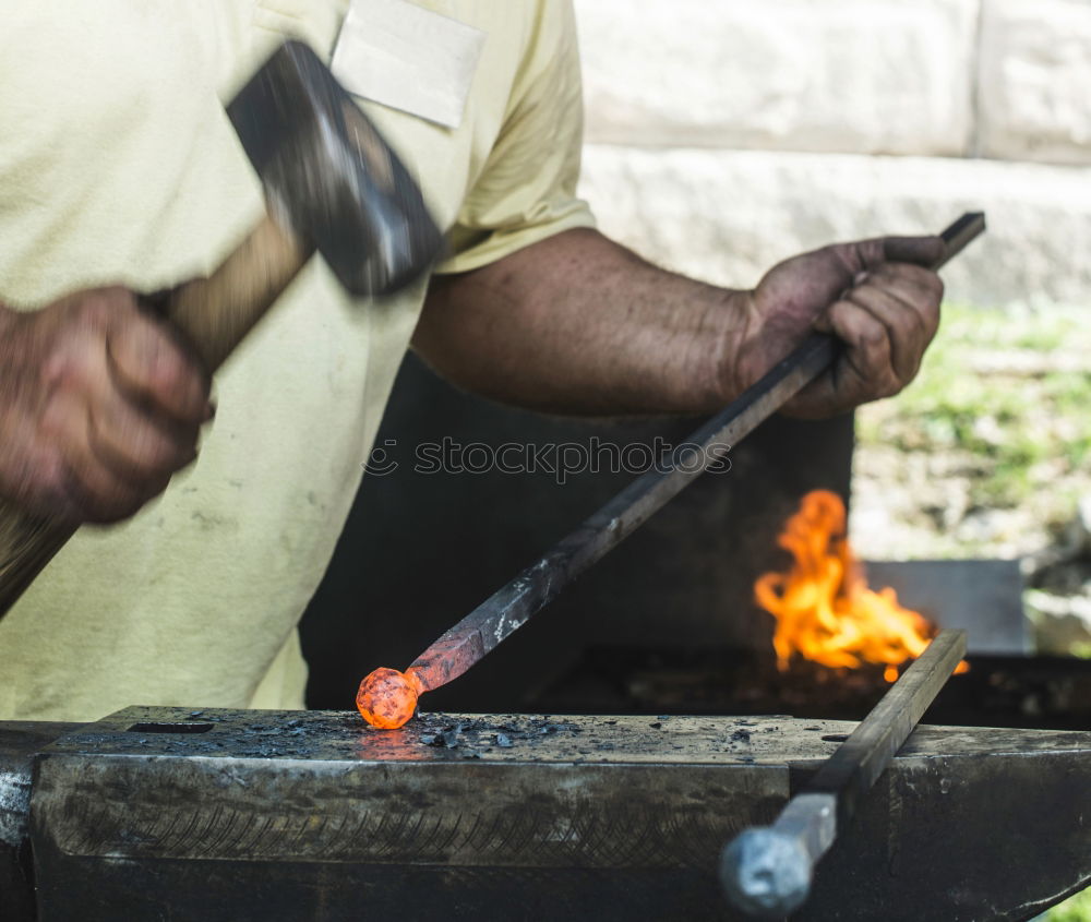 Blacksmith forges iron on anvil