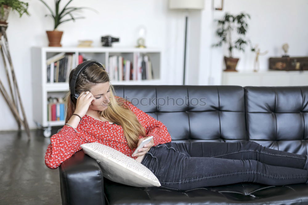 Image, Stock Photo Young woman using an smartphone and listening music while lying on a leather couch