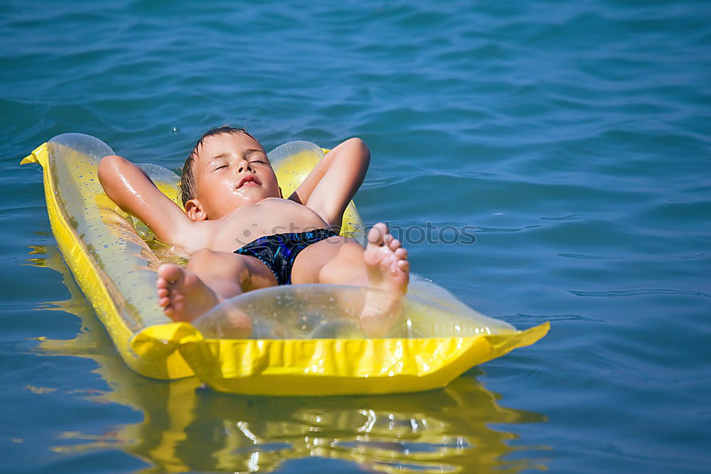 One little happy boy playing on the inflatable circle in swimming pool at the day time. Concept of friendly family.