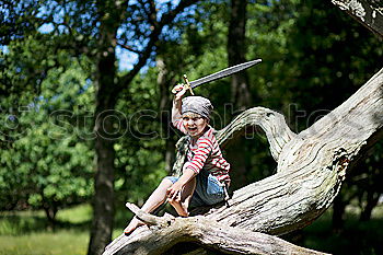 Similar – Cheerful kid in costume posing on tree