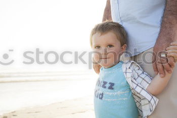 Similar – Image, Stock Photo Smiling father with his young son at the beach crouching down on the sand with a smile as the boy stands alongside him