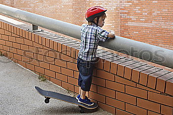 Similar – boy sitting on ground leaning on a wall, taking a selfie