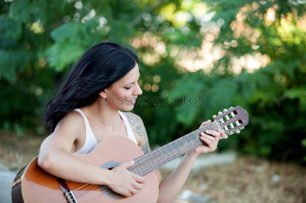 Mädchen spielt Ukulele im Gartenstuhl