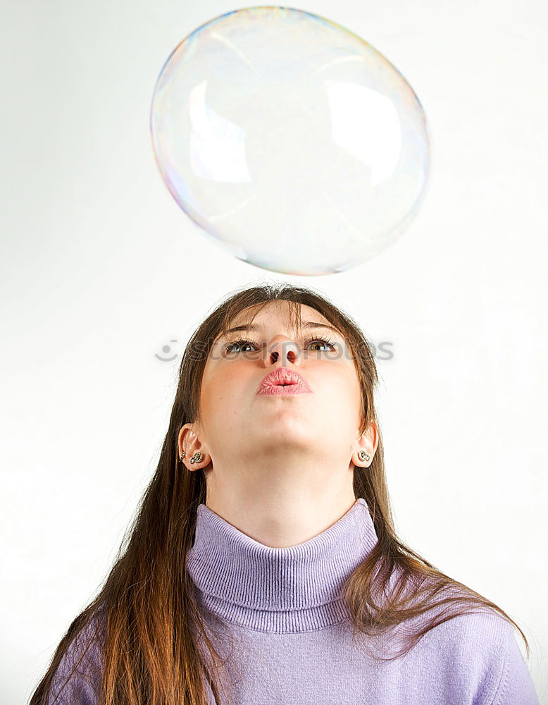 Thoughtful, dreamy, sweet girl with a white balloon in her hand in the garden, looks into the camera. Dear birthday girl outside in the nature is happy about a gift balloon for her party, holds it tight and puts it in her mouth.