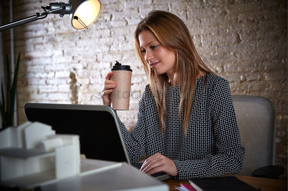 Young businesswoman working on laptop and drinking coffee