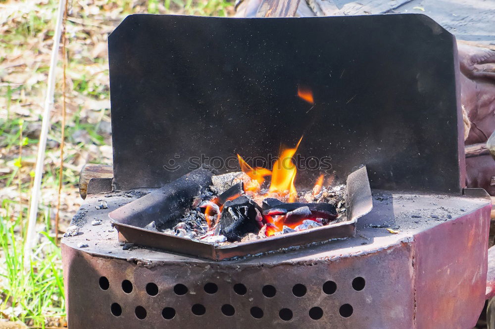 Ein großer Kochtopf hängt über offenem Feuer einer Feuerschale.