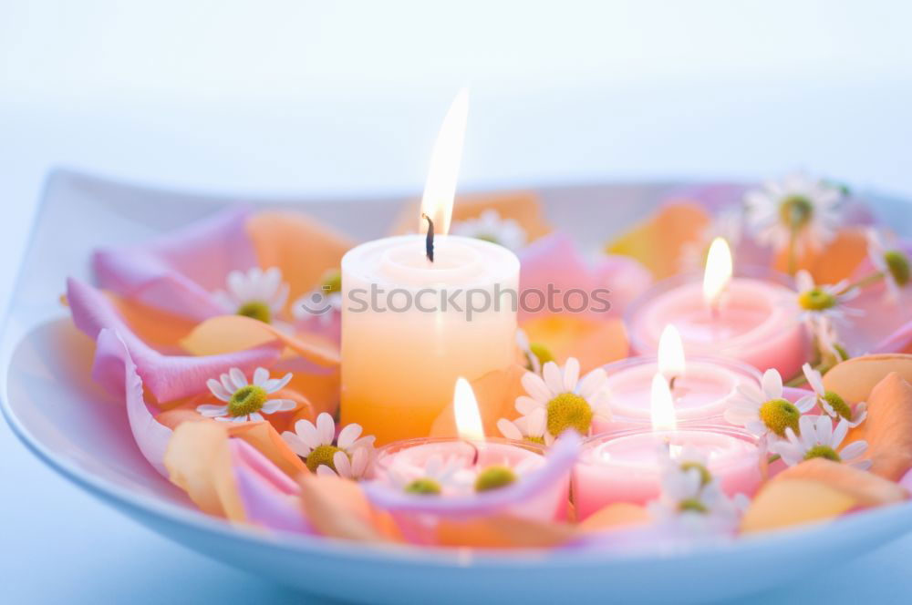 colourful spring flowers in white water bowl with three burning candles