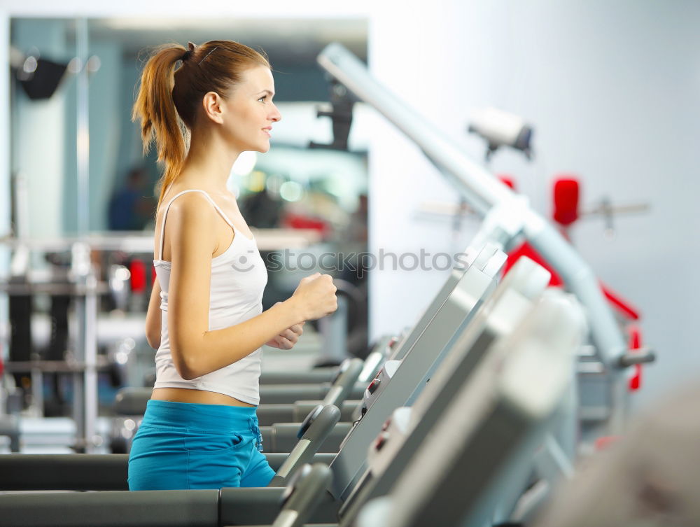 Woman drinking water while training on treadmill