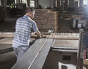 Similar – Carpenter with circular saw cutting a wooden plank