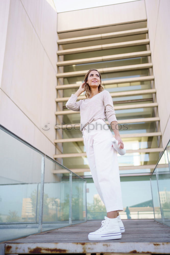 Beautiful young woman standing next to modern building.