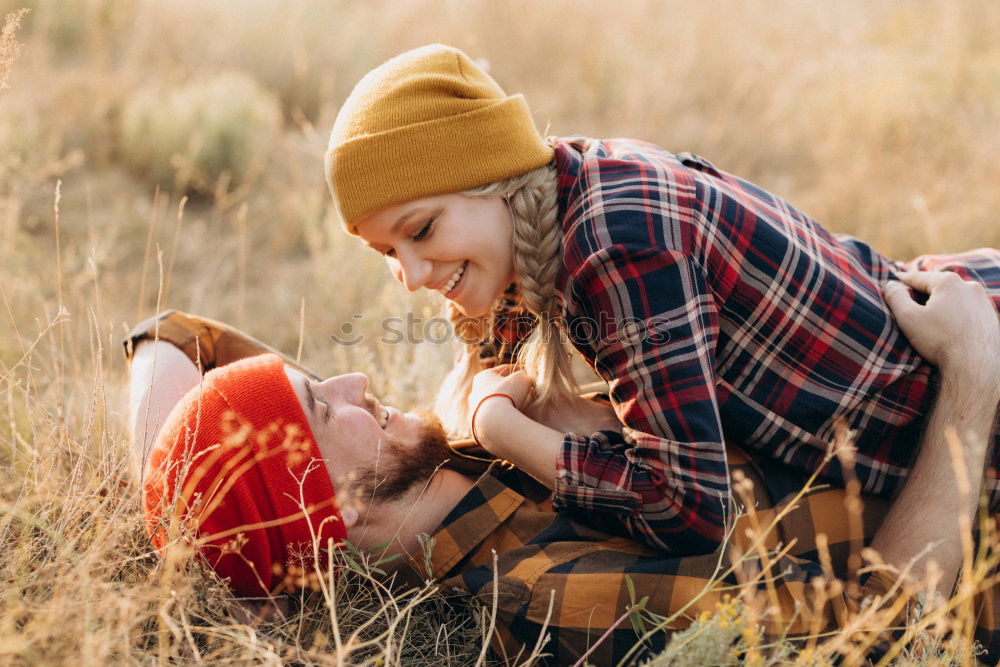 Young couple under blanket with hot drink kissing outdoors