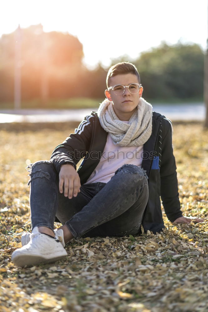 Similar – Stylish smiling teenager sitting on the ground in a city park