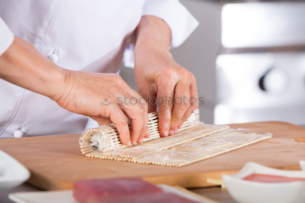 Woman chef hands rolling up japanese sushi