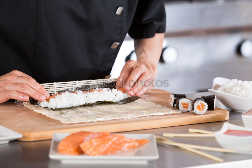 Closeup of woman chef cutting japanese sushi roll