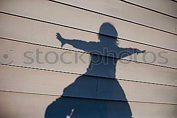 Male shadow with gun on wall