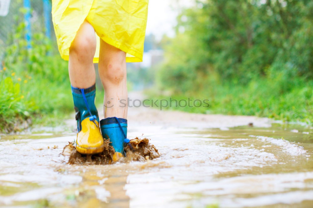 Similar – Legs in red trousers and green rubber boots jumping in a muddy puddle, so that the mud flies up