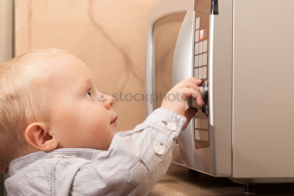 Similar – Baby toddler sits interested and curious in front of washing machine on the floor