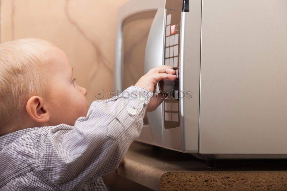 Similar – Baby toddler sits interested and curious in front of washing machine on the floor