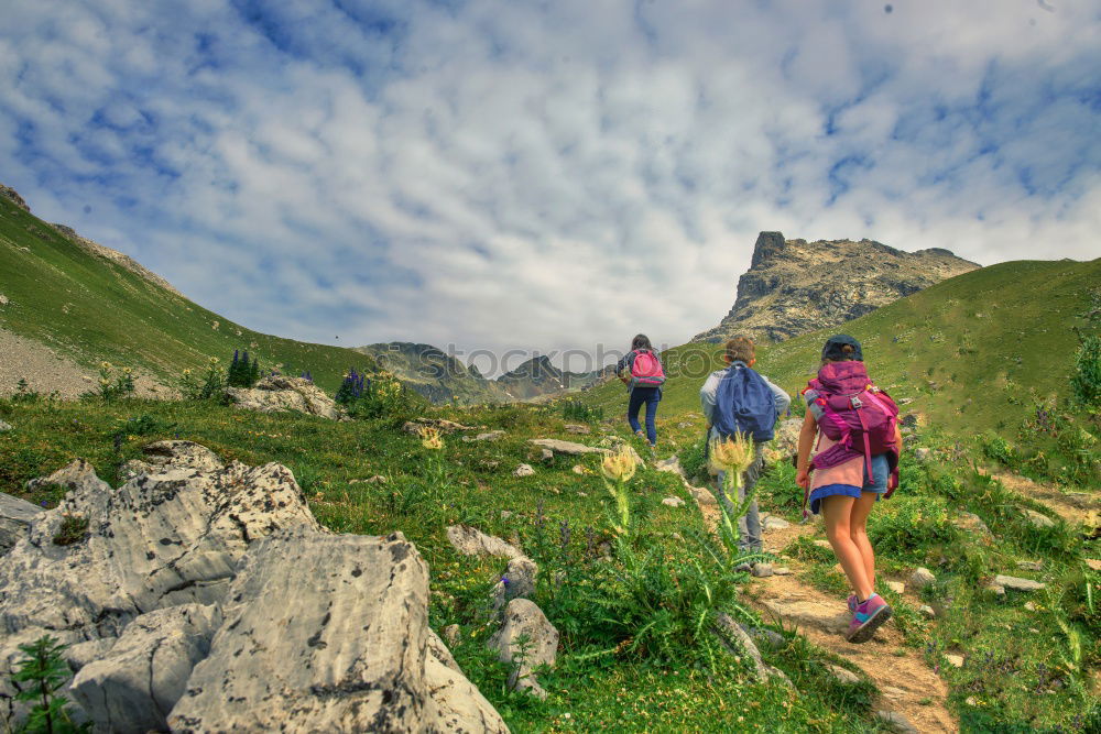 Similar – Cloud rolls over the mountains, man with red jacket and backpack stands on a path and looks into a valley