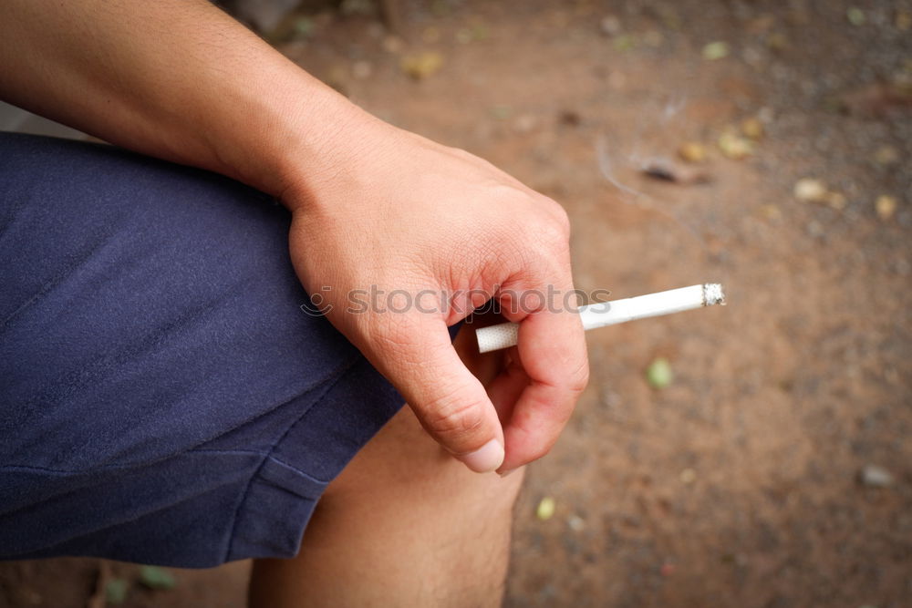 Similar – sitting man with short pants and burning cigarette in his hand