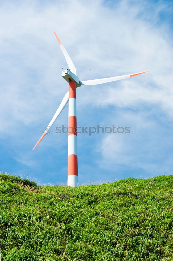 Wind turbine for renewable power generation in front of a dike on the North Sea coast, long straight road. Wind turbine