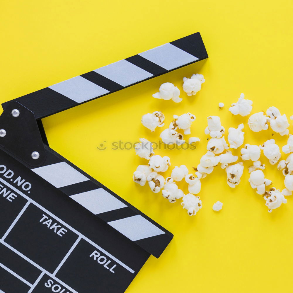 popcorn and clapboard on yellow background. Cinema concept