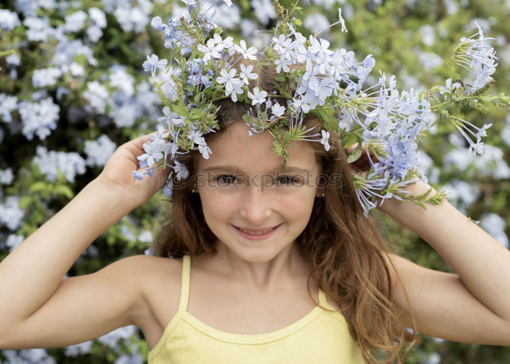 romantic portrait of happy child girl picking bouquet of beautiful blue delphinium flowers from summer garden