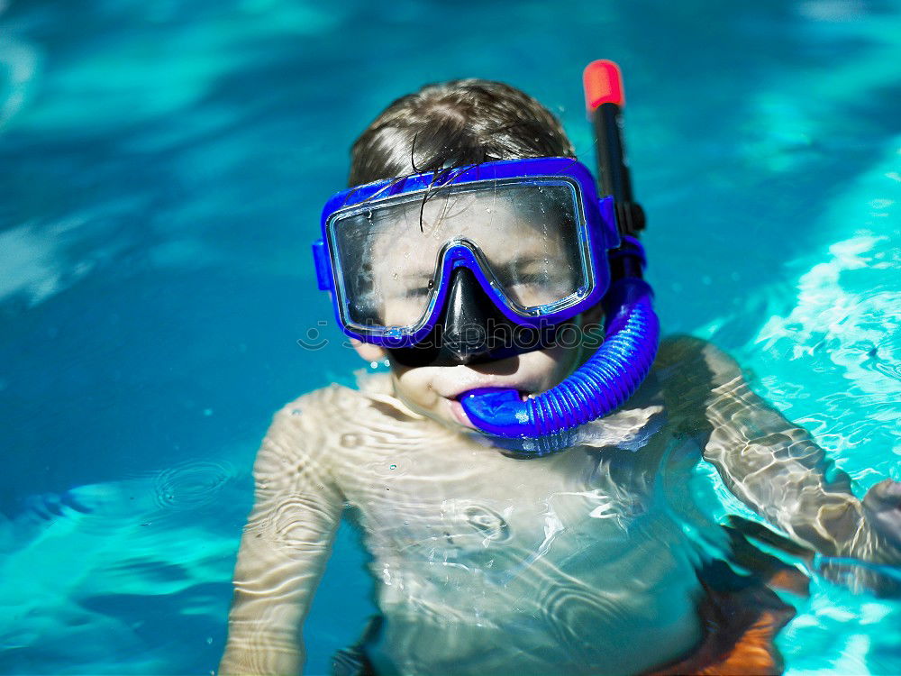 One little happy boy playing on the inflatable circle in swimming pool at the day time. Concept of friendly family.