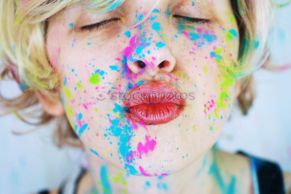 Kiss of a young woman with colorful paint in her face