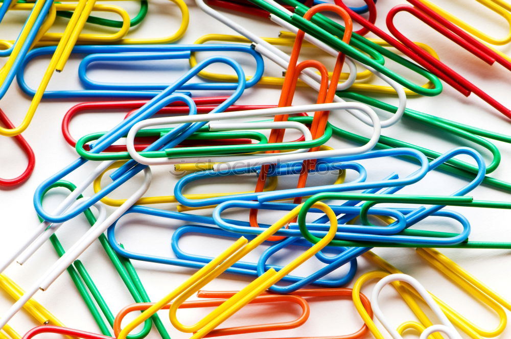 three coloured scissors in a round wire container in front of a yellow background