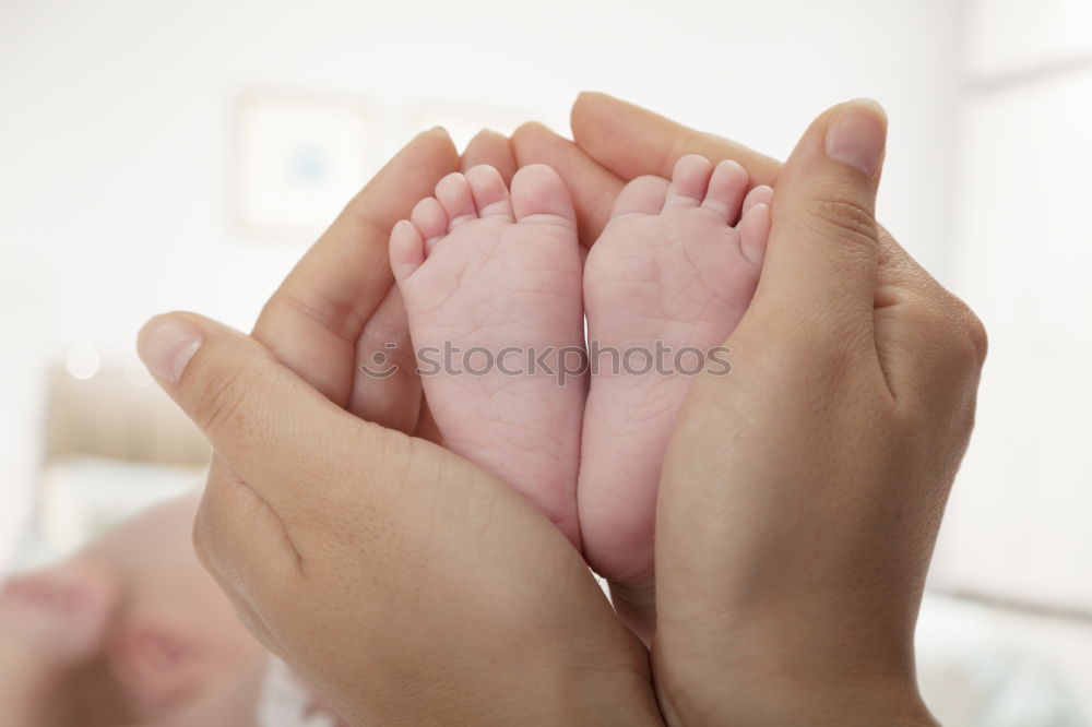 Similar – mother and father holding newborns feet in a heart shape