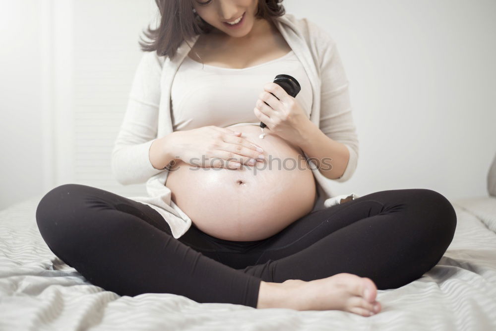 Similar – Happy pregnant woman sitting and touching her belly at home