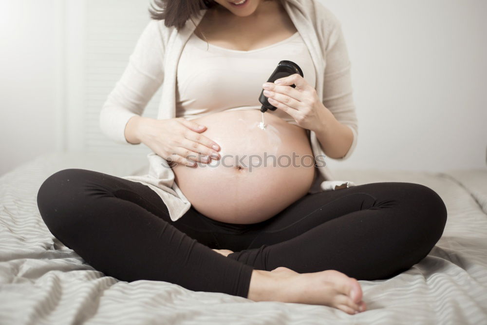 Similar – Happy pregnant woman sitting and touching her belly at home