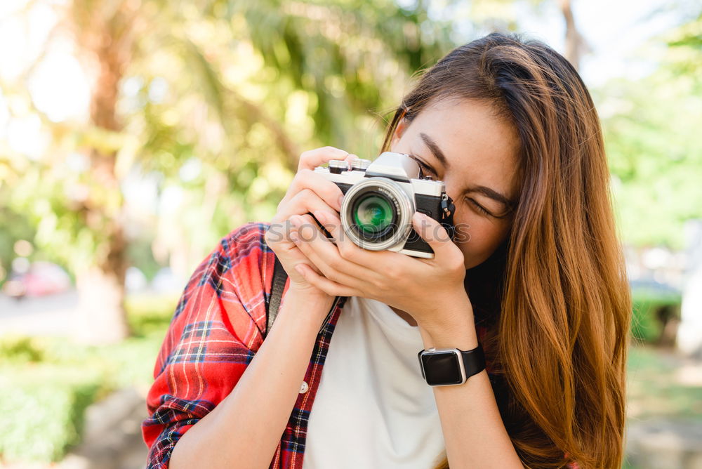 Similar – Smiling young woman using a camera to take photo at the park.