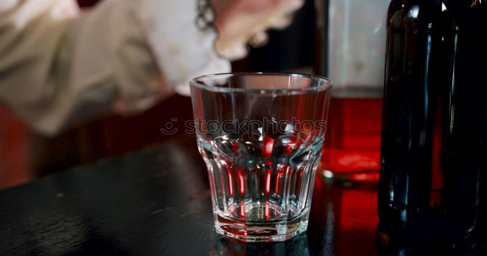 Similar – On a table there is a bottle of alcohol and a shot glass. A person’s hand is holding the shot glass.