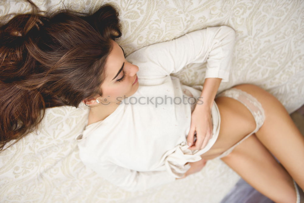 Similar – Young woman sits barefoot in undershirt on a flowered couch and looks sideways into the camera