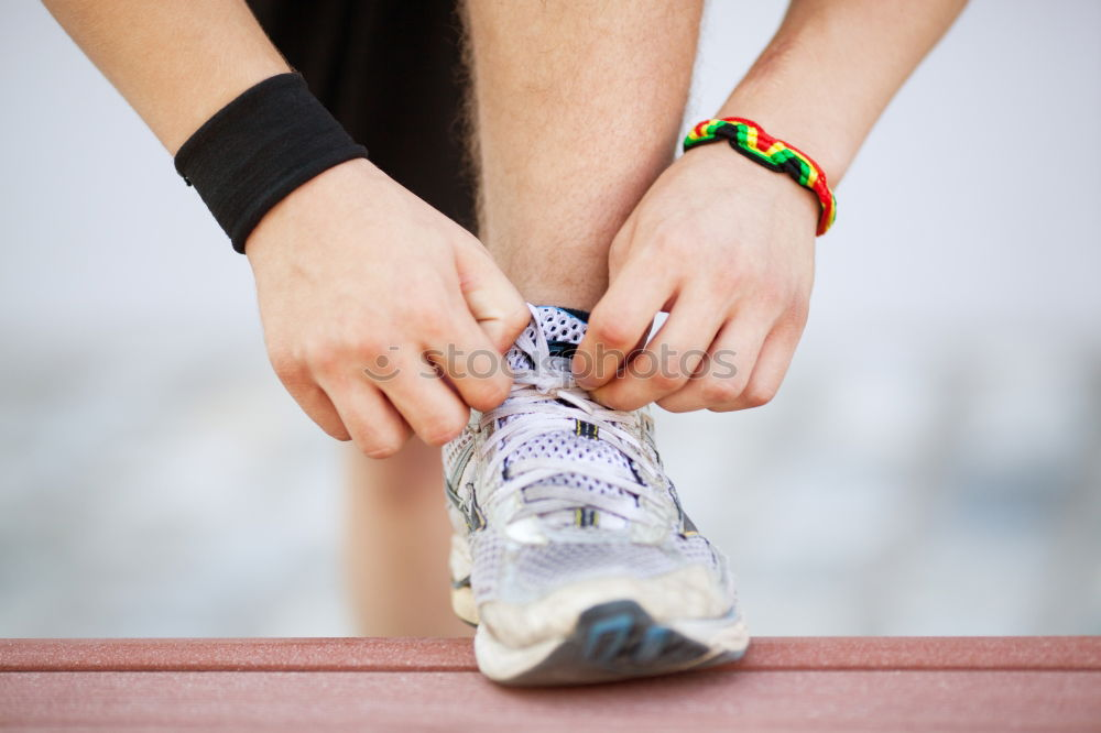 Nahaufnahme eines Mannes beim Binden von Laufschuhen mit Fuß auf der Bank. Bereitmachen vor dem Joggen. Gehen in für Sport, gesunden Lebensstil