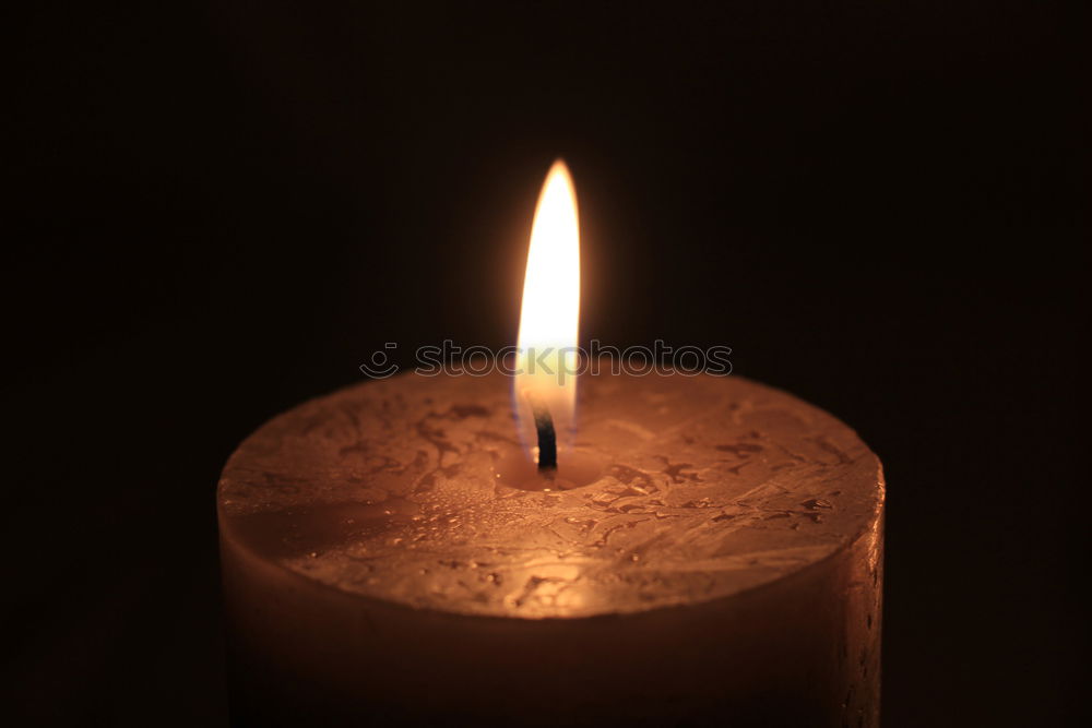 Hand holding a candle with a flame burning with warm candlelight creating cozy romantic ambience